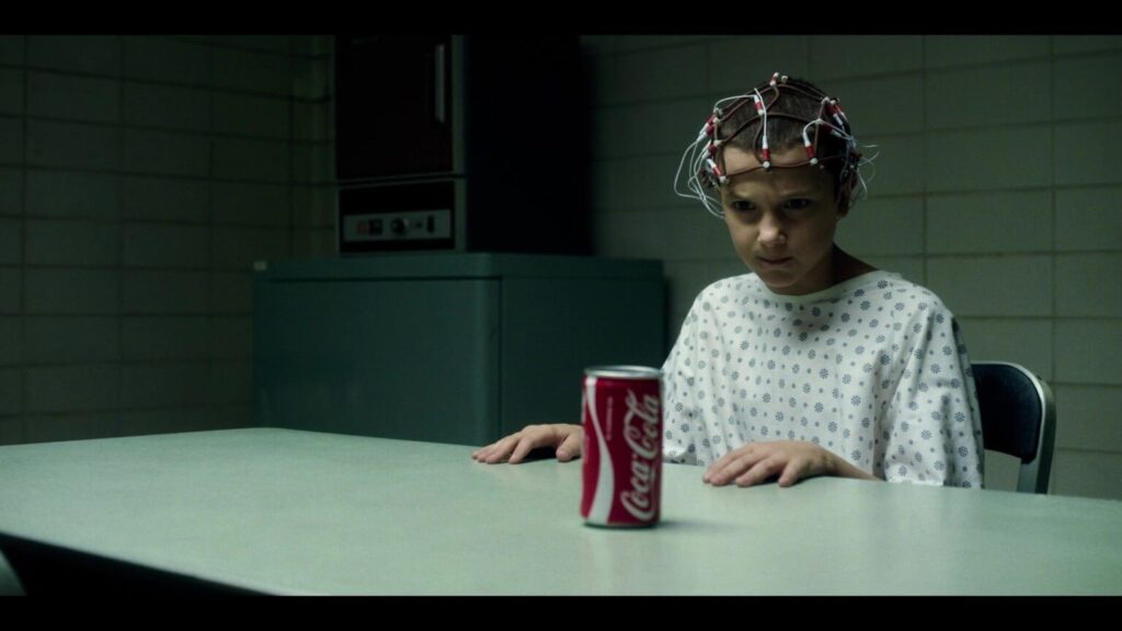 Eleven character tries to smash a can of Coca-Cola in the “stranger things” series, as an example of product placement.