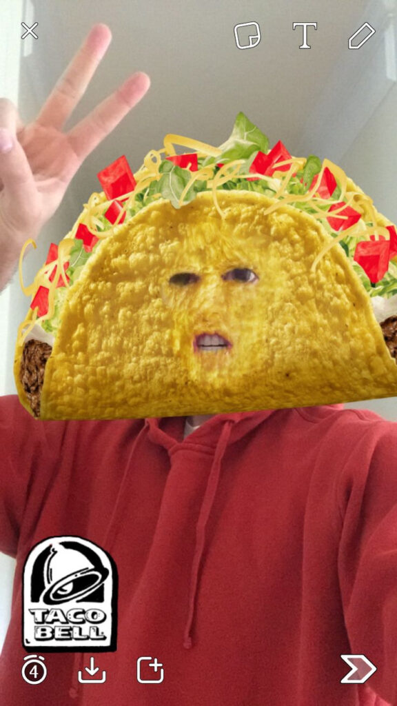 A man using the Taco Bell lens on Snapchat as an example of Sponsored content. 